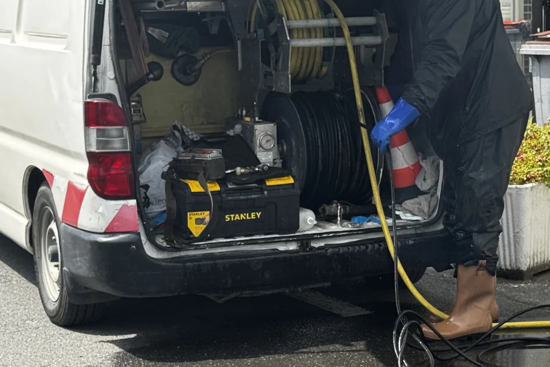 Intervention Aprime Fluides avec le camion hydrocureur : dévidoir haute pression et flexible déroulé sur chantier en Île-de-France
