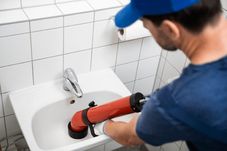 Plombier en train de déboucher un évier bouché dans une salle de bain
