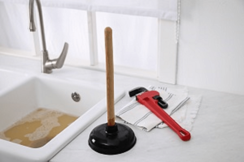 Technicien APRIME FLUIDES en train de déboucher un lavabo dans une salle de bain en Île-de-France